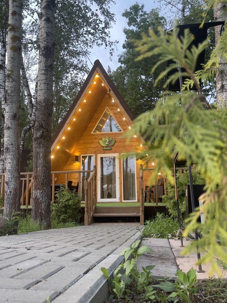 Шалаш (A-frame) среди деревьев с гирляндой